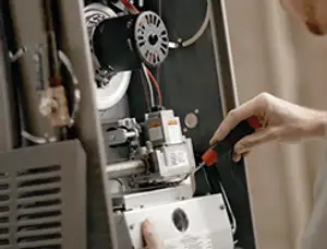 Furnace repair technician inspecting internal components and wiring in Reno, NV