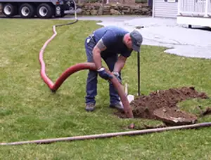 Septic pumping technician servicing a residential septic tank with a vacuum hose in Reno, NV
