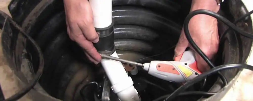 Sump pump installation technician connecting PVC discharge piping in Reno, NV