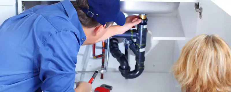Plumber repairing under-sink drain pipes and fittings in Reno, NV