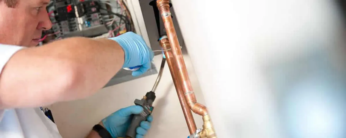 Water heater repair technician testing copper pipe connections and controls in Reno, NV